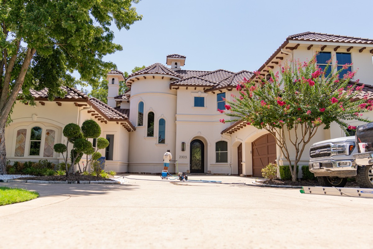 A large stucco home in Weatherford with Caleb at work across the front.